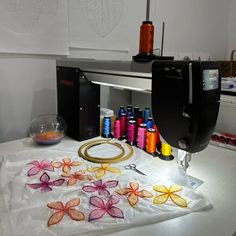 the sewing machine is next to some thread and flowers