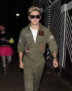 a man in an air force pilot's uniform walking down the street at night