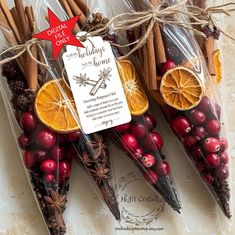 three oranges and cinnamon sticks are wrapped in cellophane to look like christmas decorations