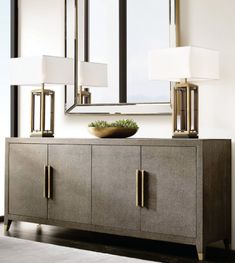 a sideboard with two lamps and a mirror