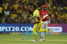 two men in yellow and red uniforms playing a game of cricket