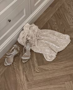 a pair of shoes are laying on the floor next to a white robe and high heels