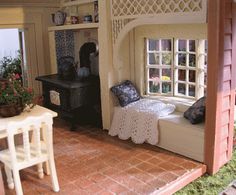 a doll house with a bed, table and chair in the living room next to an open window