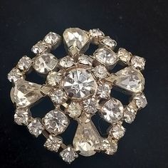 This vintage rhinestone brooch features a 1.5" D design with clear rhinestones and silver tone metal. Silver Rhinestone Brooches For Formal Occasions, Silver Rhinestone Brooches For Anniversary, Formal Silver Brooches With Rhinestones, Formal Silver Rhinestone Brooches, Formal Rhinestone Costume Brooches, Vintage Rhinestone Pins For Party, Vintage Jeweled Crystal Brooches, Vintage Rhinestone Party Pins, Vintage Crystal Jeweled Brooches