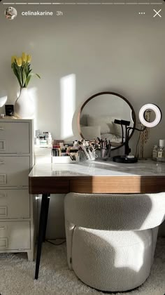 a desk with a mirror and some drawers in the corner next to a vase filled with flowers