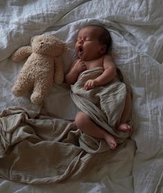 a baby sleeping next to a teddy bear