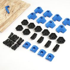 blue and black plastic parts are laid out on a white surface next to a piece of wood