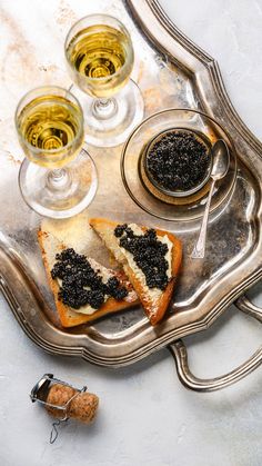 a silver tray topped with two slices of toast and three glasses of wine next to it