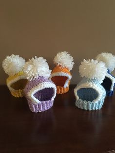 four knitted hats sitting on top of a wooden table