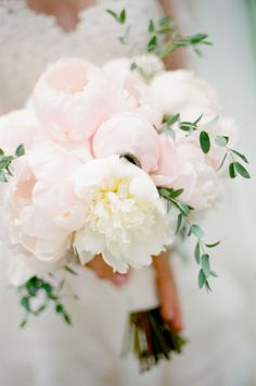 a bridal holding a bouquet of white and pink peonies in her hands