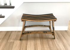 a wooden stool sitting on top of a hard wood floor next to a stair case