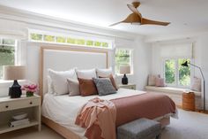 a bedroom with a bed, two windows and a ceiling fan in the middle of it