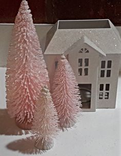 two pink christmas trees in front of a white house and window sill with snow on the windowsill