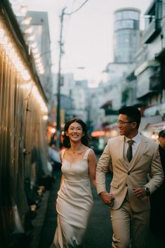 a man and woman are walking down the street holding hands as they smile at each other