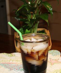 there is a drink with ice in it on the table next to a potted plant