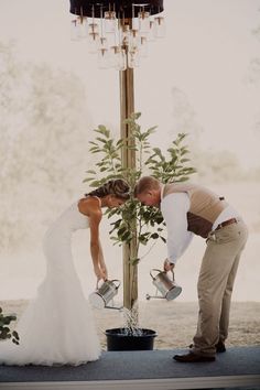 a bride and groom are pouring water into their buckets at the end of their wedding ceremony