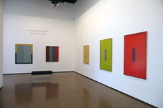 an empty room with three paintings on the wall and two benches in front of them