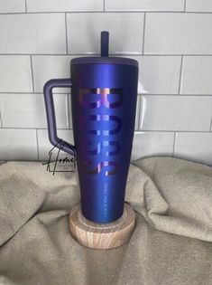 a blue coffee cup sitting on top of a wooden stand next to a white tile wall