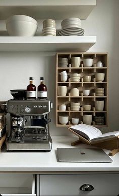 an espresso machine sitting on top of a counter next to plates and cups