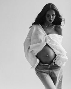 a black and white photo of a woman with her stomach exposed, wearing an off the shoulder top