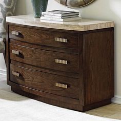 a wooden dresser sitting next to a wall with a mirror on top of it and a plant in the corner