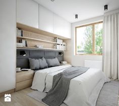 a bedroom with white walls and wood flooring has a large bed, built - in shelving unit, and two windows