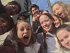 a group of young people standing next to each other in front of a house with their mouths open