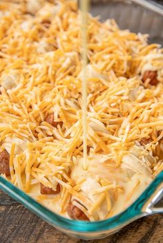 a casserole dish with cheese being poured into it