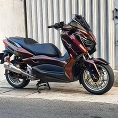 the motorcycle is parked on the side of the road near a building with metal sidings