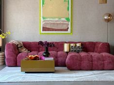 a living room with pink couches and colorful art on the wall behind it,