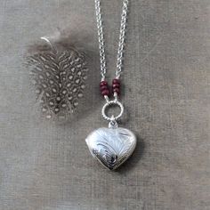 This sterling silver locket is engraved with a swirl pattern on the front and back.  The heart shaped locket opens revealing two frames awaiting your treasured photos.  The pendant is suspended from a braided ring accented with stacks of little genuine ruby rondelles (July birthstone) and set on a sterling silver rolo chain finished with a lobster clasp.The locket is also available in a round shape; this option is available at checkout.  All other birthstone also available.  Locket 20mmNecklace Elegant Etched Heart Pendant Jewelry, Silver Etched Necklace For Valentine's Day, Valentine's Day Silver Etched Necklace, Silver Heart Locket Necklace Spiritual Style, Adjustable Heart-shaped Locket Jewelry, Silver Heart-shaped Etched Necklace, Silver Heart-shaped Etched Jewelry, Adjustable Heart-shaped Locket, Etched Heart Silver Jewelry