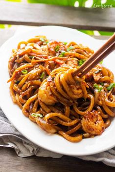 stir fry noodles with chicken and vegetables on a white plate topped with chopsticks