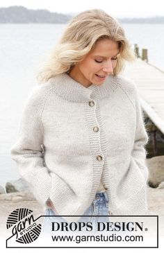 a woman wearing a white cardigan by the water