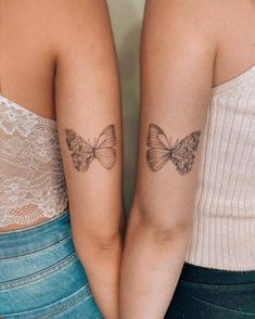 two women with matching butterfly tattoos on their arms, both holding each other's hands