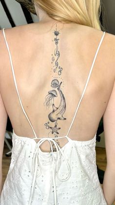 the back of a woman's white dress with fish tattoos on her upper and lower back