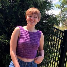 a woman standing in front of a fence with her hand on her hip and smiling at the camera