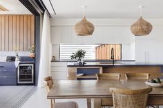 an open kitchen and dining room area with wooden table, chairs, sink and oven