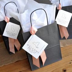 two black and white paper bags with pink bows on them are sitting on a table