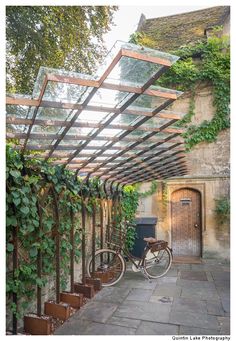 an old bicycle is parked under a pergolated structure with ivy growing on it