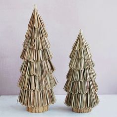 two small trees made out of straw sitting next to each other on a white surface