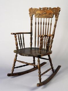 an antique rocking chair with carved wooden arms and legs, on a white background in front of a wall