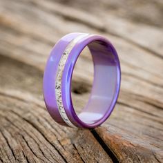 a purple ring with white speckles on it sitting on a piece of wood