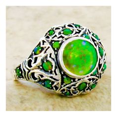 This exquisite piece is a Vintage Estate ring, featuring a green lab-created fire opal as its centerpiece, set within an intricate filigree design. Complementing the central stone are green lab-created opal accent stones, adding to the ring's overall allure. The ring is crafted from 925 solid sterling silver, ensuring both quality and durability. The dimensions of the ring are noteworthy, with the top measuring just over 1/2 inch in length, providing a substantial and elegant presence on the fin Vintage Green Opal Round Ring, Green Opal Birthstone Jewelry, Green Sterling Silver Filigree Ring, Green Opal Sterling Silver Wedding Ring, Green Filigree Ring For May Birthstone, Green Opal Ring For May Birthstone Gift, Unique Green Cabochon Opal Ring, Green Opal Cabochon Ring, Ornate Green Filigree Ring As A Gift