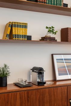 a coffee maker on a wooden shelf next to some books and other items in a room