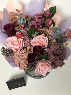 a vase filled with lots of flowers on top of a white table next to a black box