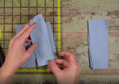 two hands holding blue cloth on top of a wooden table