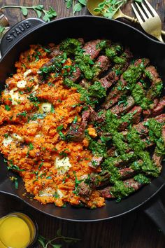 a skillet filled with meat and vegetables next to a glass of orange juice