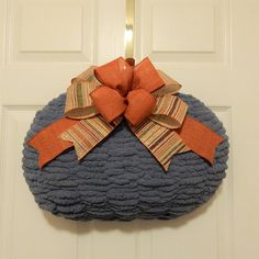 a knitted wreath with orange bows hanging on the front door