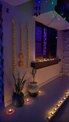 two vases filled with plants sitting on top of a counter next to candles and lights