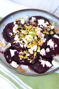 a plate with beets, nuts and feta cheese on it sitting on a table